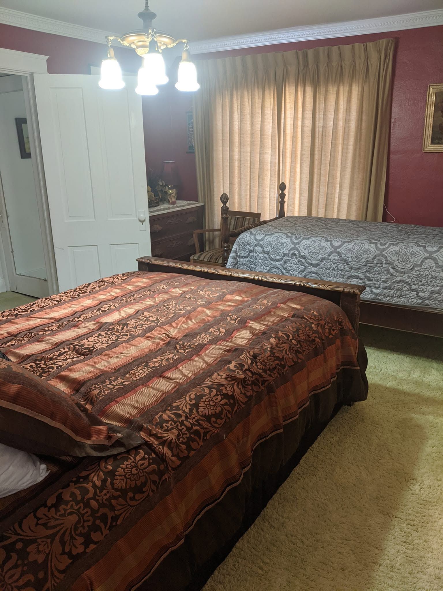 Bedroom with two beds, a ceiling light, and beige curtains over a window