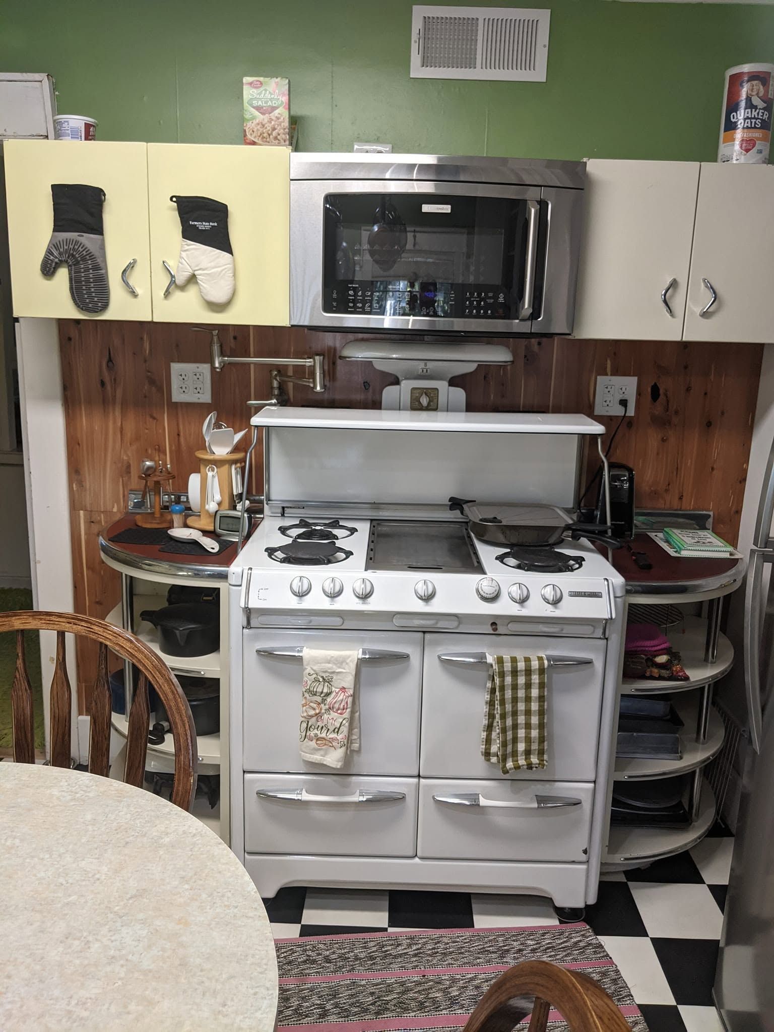 Small kitchen with a white stove, microwave above, beige cabinets, and a checkered floor.