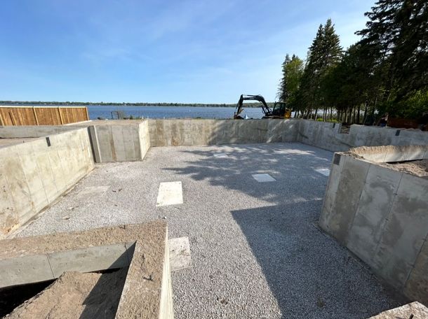 Concrete foundation walls surrounding  a gravel floor at a lakeshore construction site