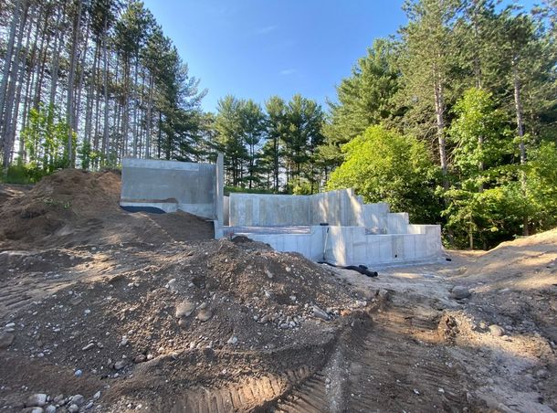 Concrete foundation walls for a building under construction, surrounded by a forest background