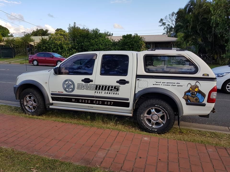 White utility pickup truck with company logos parked on a brick sidewalk in a suburban street — Bad Bugs Pest Control in Rockhampton, QLD