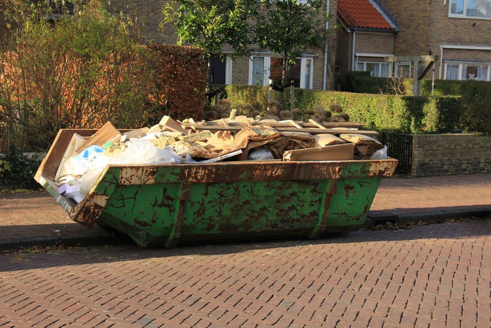 Green Dumpster Overflowing With Debris on a Brick-paved Street — Bad Bugs Pest Control in Rockhampton, QLD