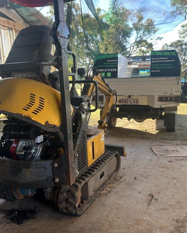 Yellow Mini Excavator Parked Beside a White Truck — I & J Mechanical in Deeragun, QLD