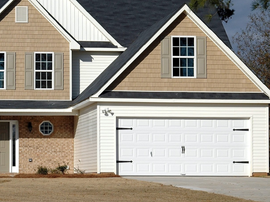 Suburban house exterior with beige siding, brick front, and white garage door