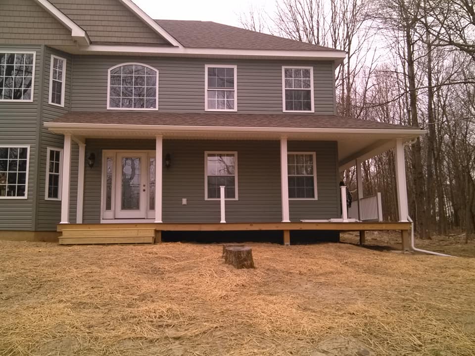 Two-story gray house with a covered front porch and sloped yard