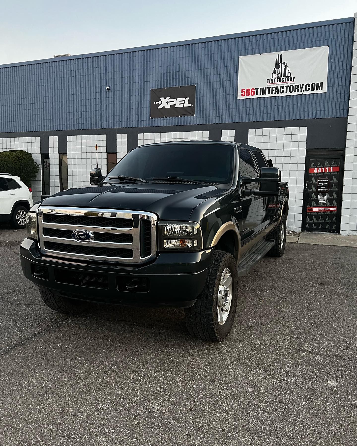 Black Ford pickup truck parked outside a blue auto service building.