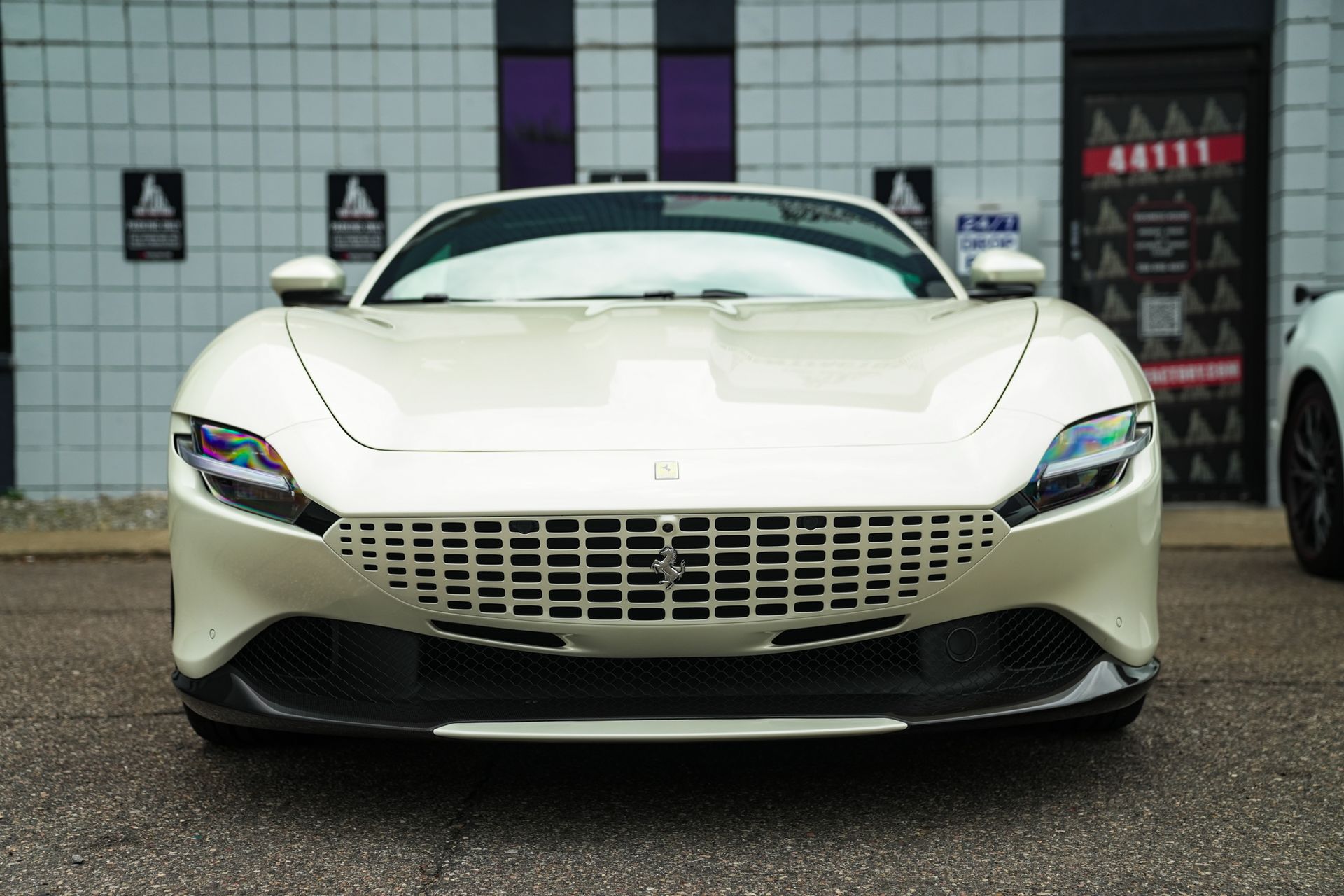 White sports car parked in front of a building, front view