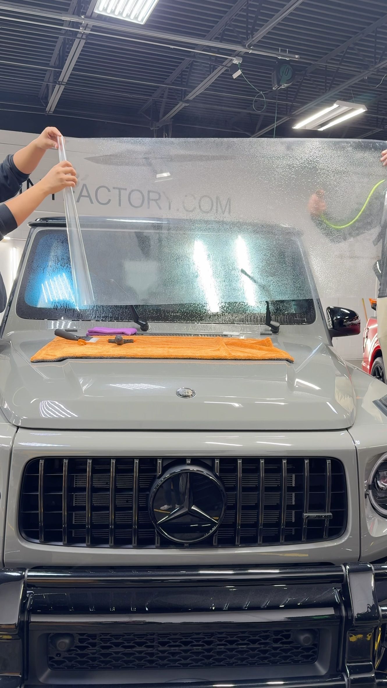 White SUV under a car wash spray, front view with wet windshield and grille