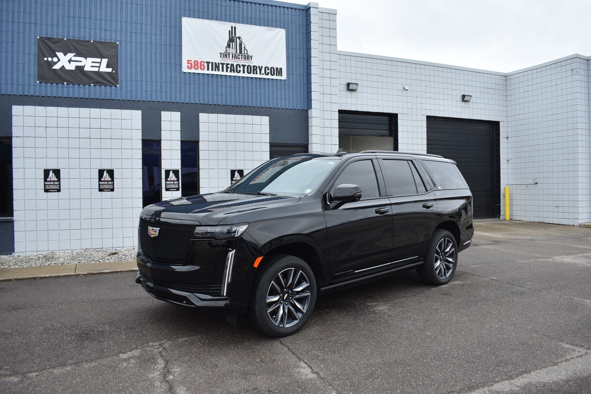 Black SUV parked outside an auto shop building on a cloudy day