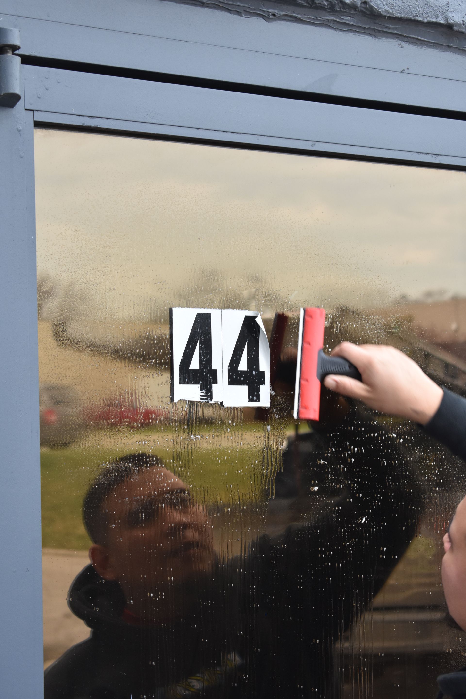 Hand placing a red tag next to house number 44 on a frosted glass door