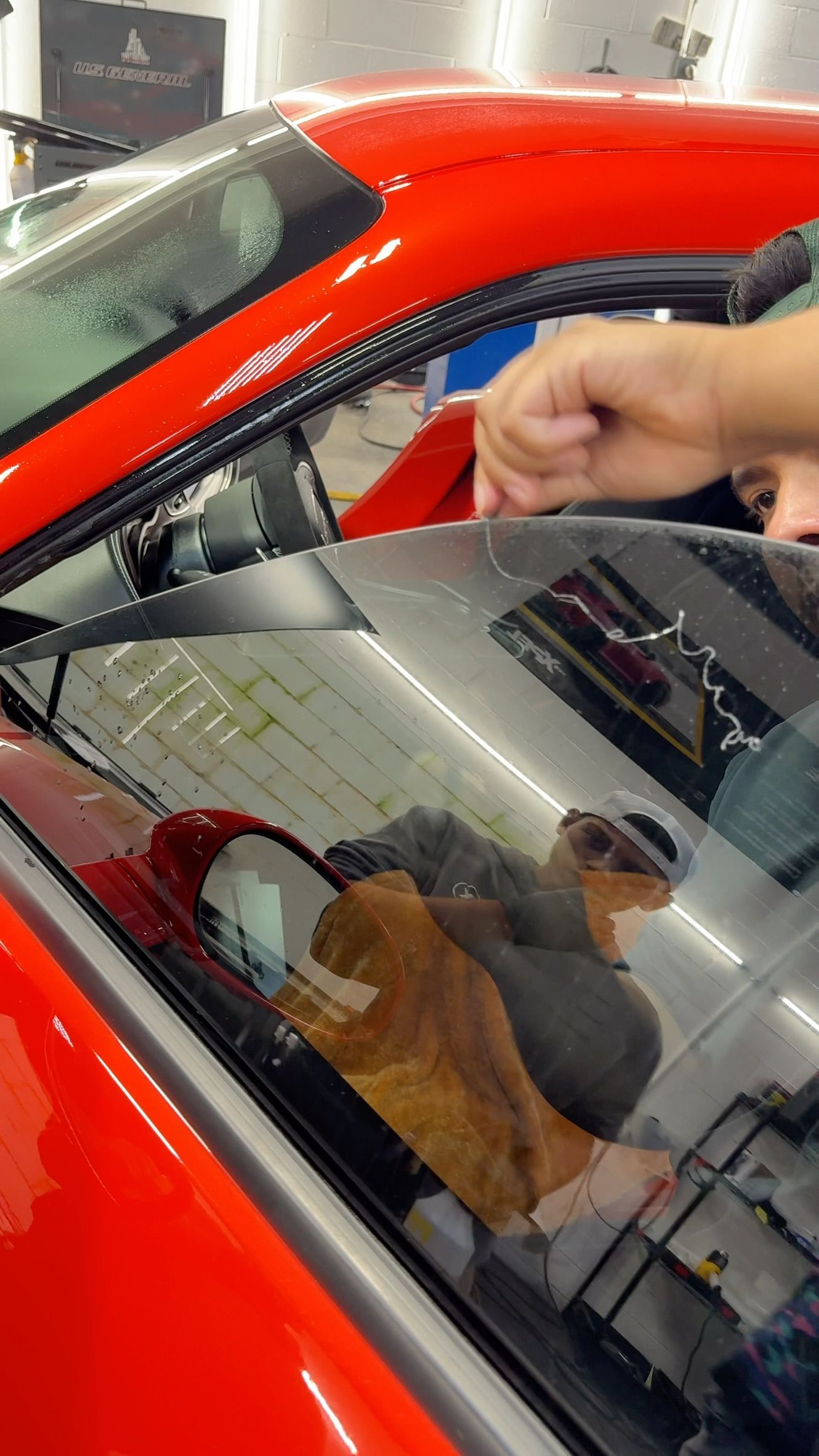 Red car in garage with a hand pressing on the windshield near a stuffed toy inside
