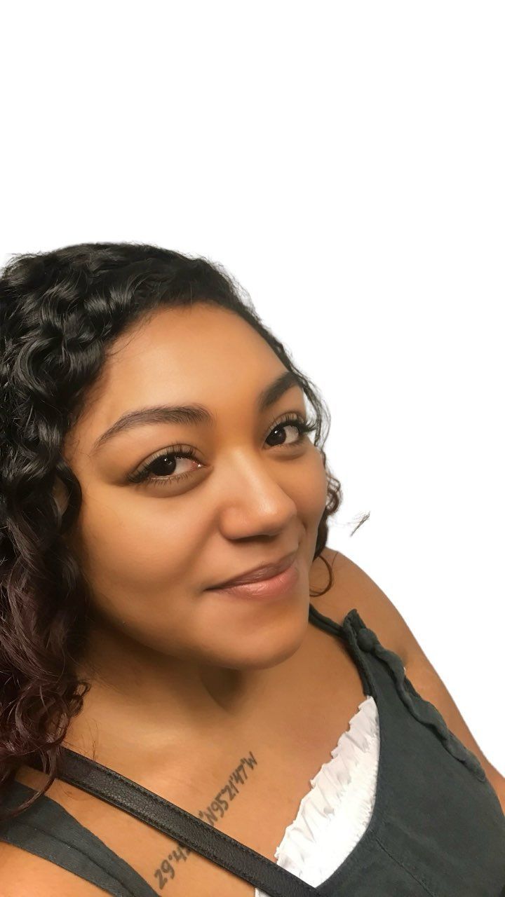 A woman with curly hair is wearing a purple dress