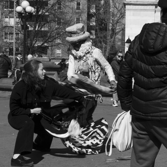 Woman interacting with street performer in ornate outfit, Washington Square Park, NYC.