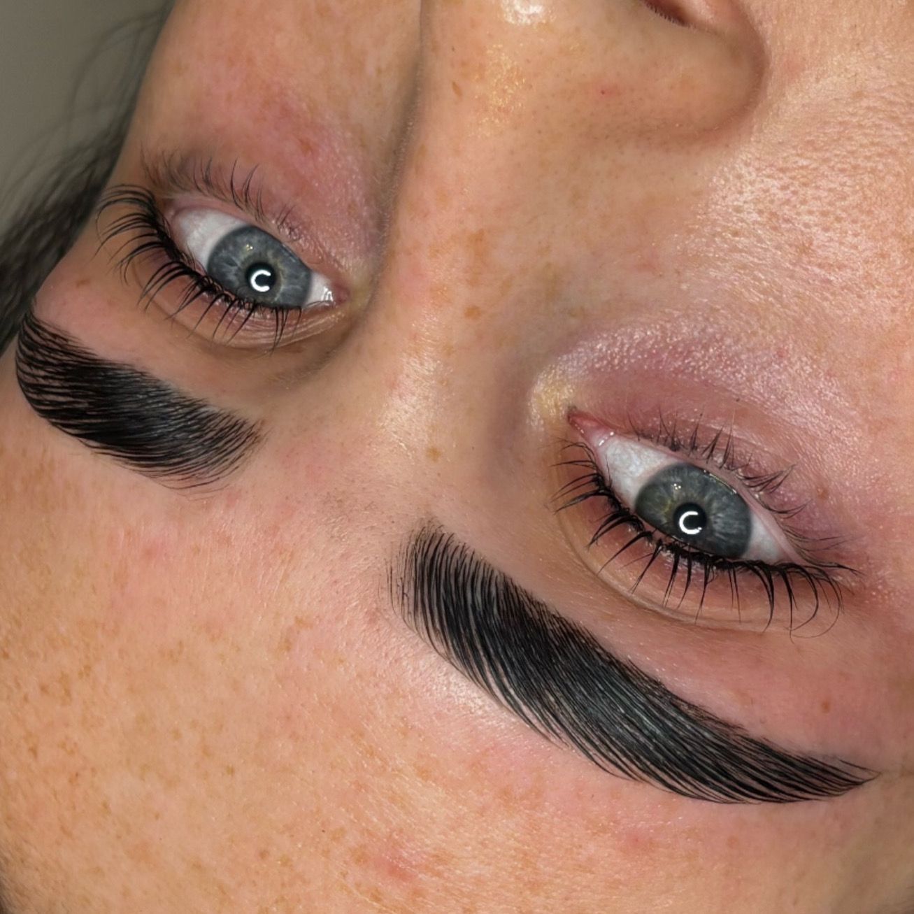 Close-up of a face with blue eyes and thick black eyebrows, shown upside down