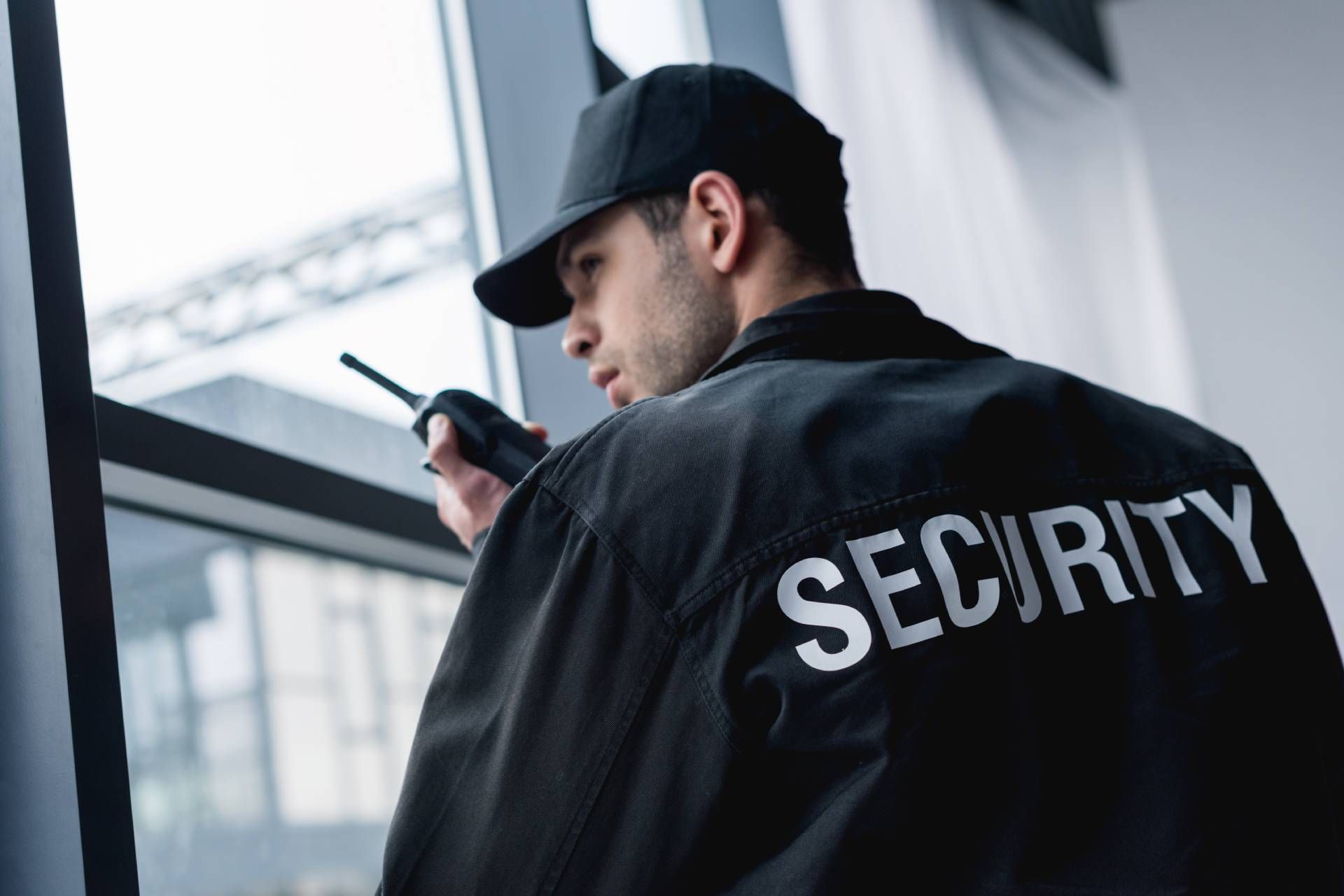 Professional security guard in corporate office building talking on walkie-talkie.