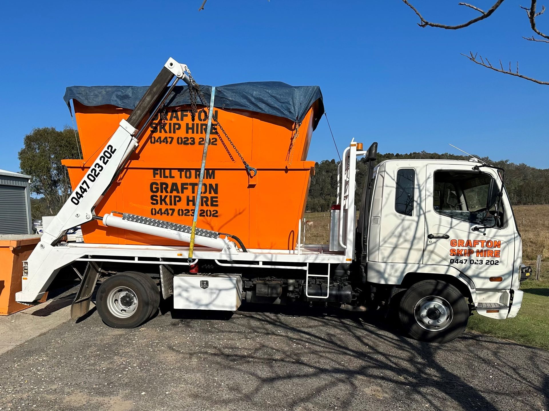 A Green Dumpster Filled With Bricks is Sitting in the Grass — Grafton Skip Hire–Zims Bins in South Grafton, NSW