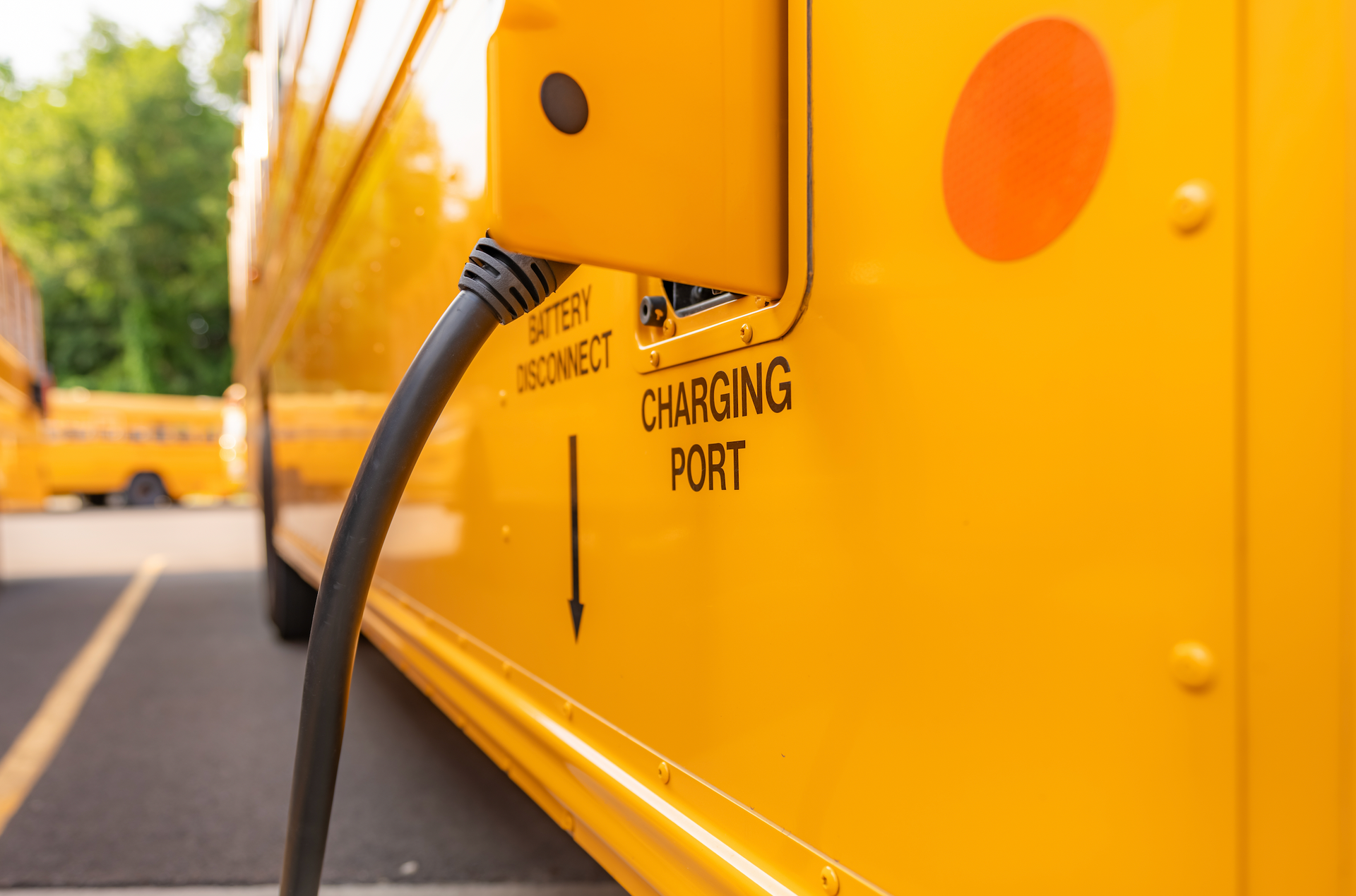A yellow school bus is being charged with a charger.