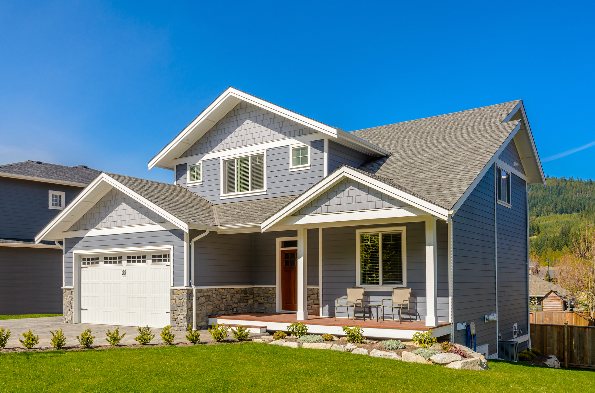 A large gray house with a white garage door and a porch.