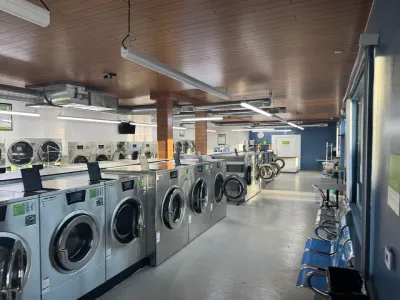A person is putting a white shirt in a washing machine.