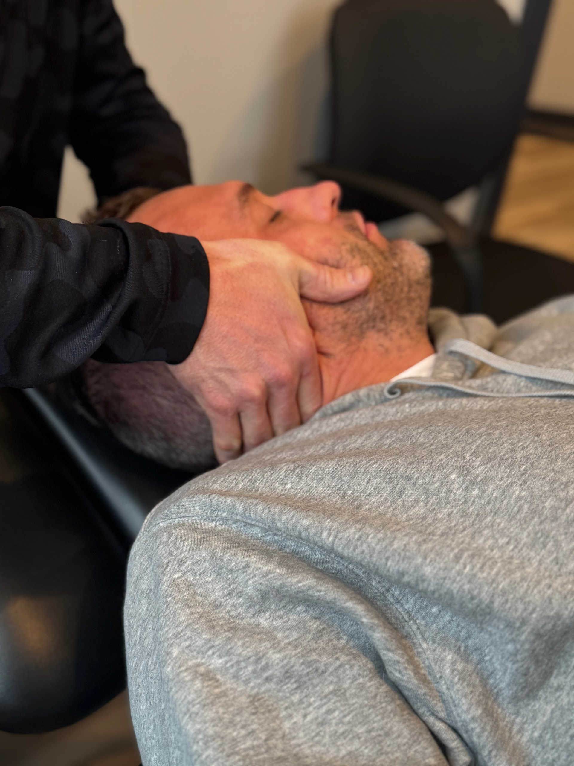 Person receiving a neck adjustment from a practitioner in a clinic setting