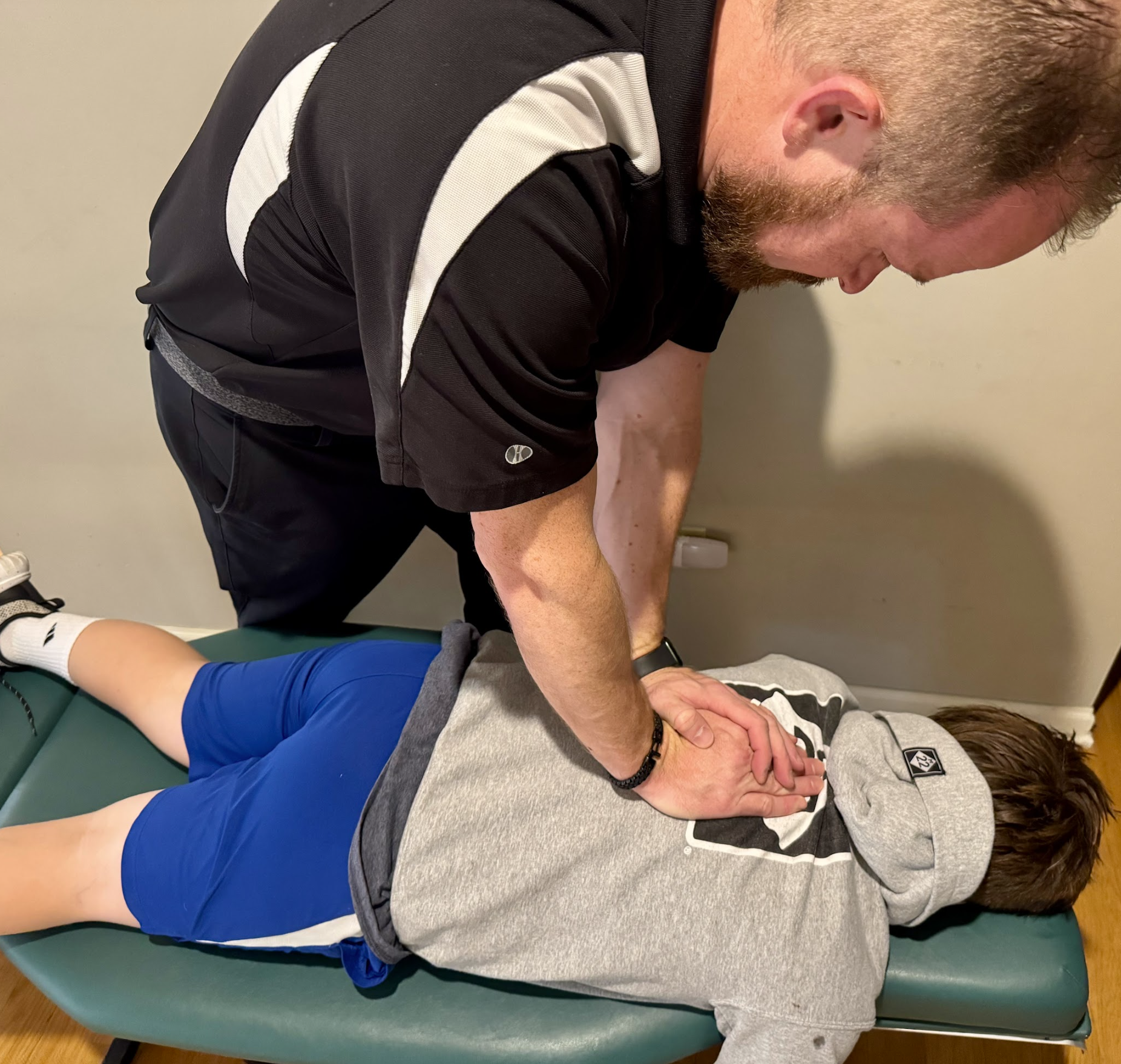 Physical therapist pressing on a patient’s lower back during treatment on a padded table