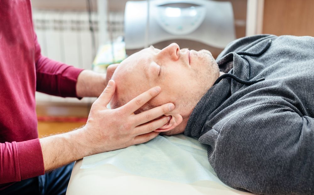 a man is laying on a bed getting a head massage .