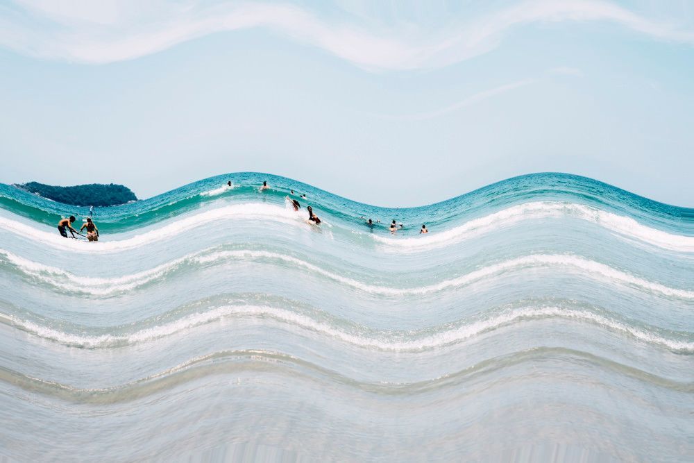 Pequenos nadadores em ondas turquesas ao longo de uma praia de areia clara.