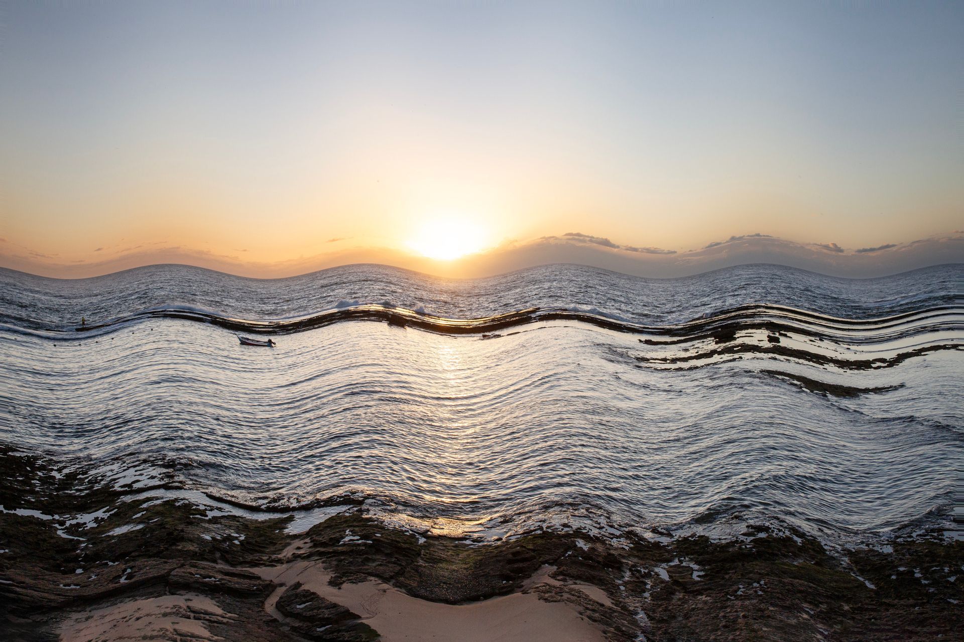 Nascer do sol sobre as águas ondulantes do oceano, com o sol brilhante próximo ao horizonte.