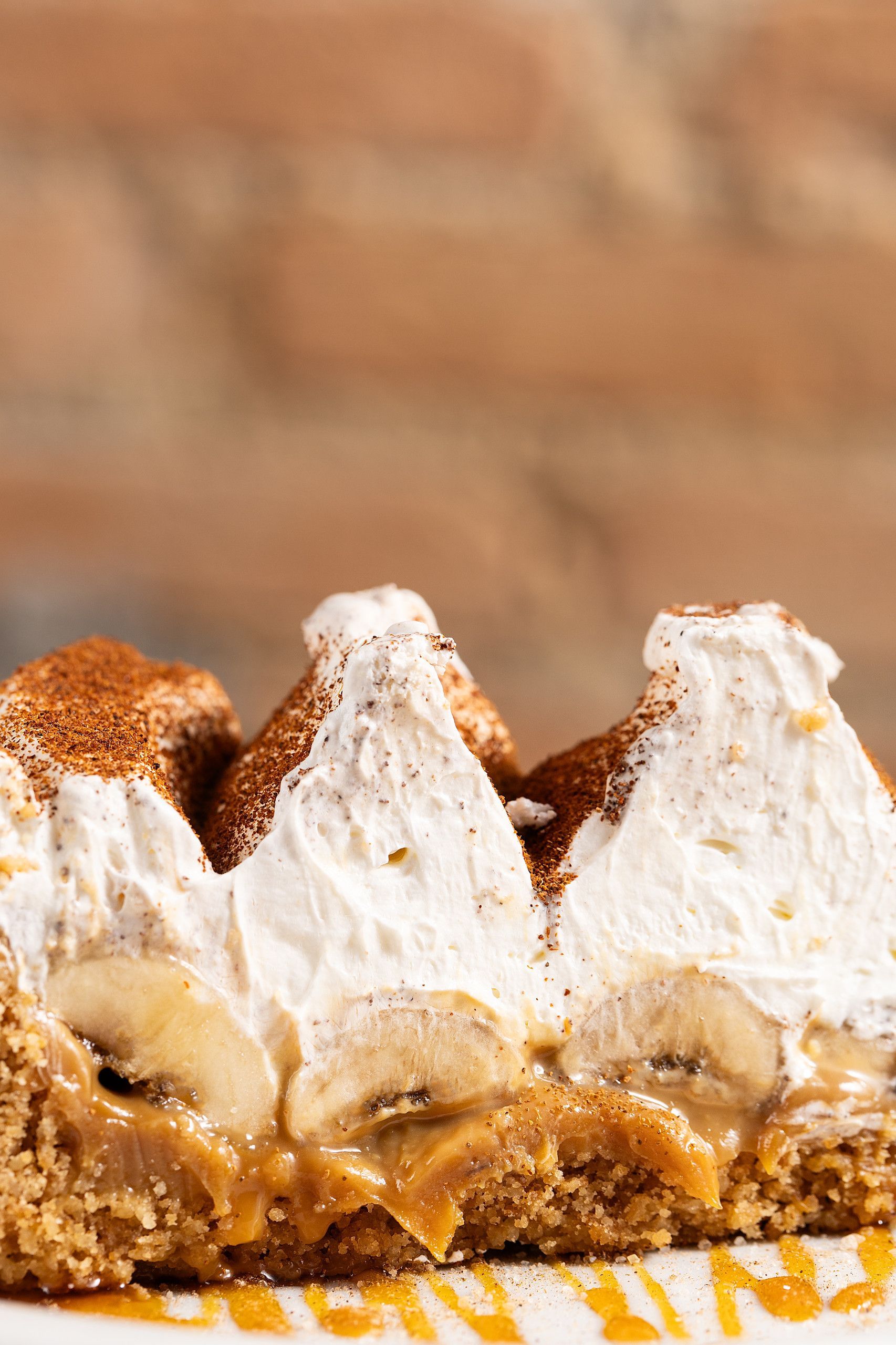 Três barras de sobremesa cobertas com chantilly e com uma crosta dourada e crocante, servidas em um prato amarelo.