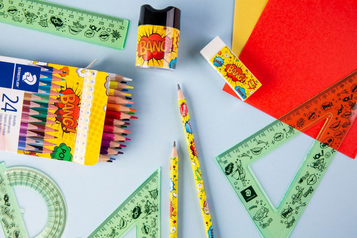 Materiais escolares coloridos — lápis de cor, réguas, borrachas e cadernos — dispostos sobre um fundo azul claro.