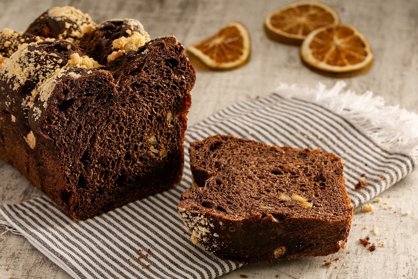 Fatias de bolo de chocolate com rodelas de laranja desidratada sobre um pano listrado.
