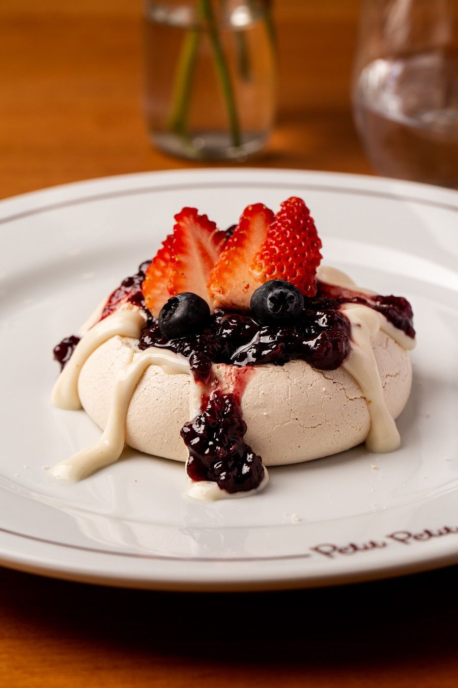 Sobremesa com morangos e frutas vermelhas em um prato branco, em um restaurante.