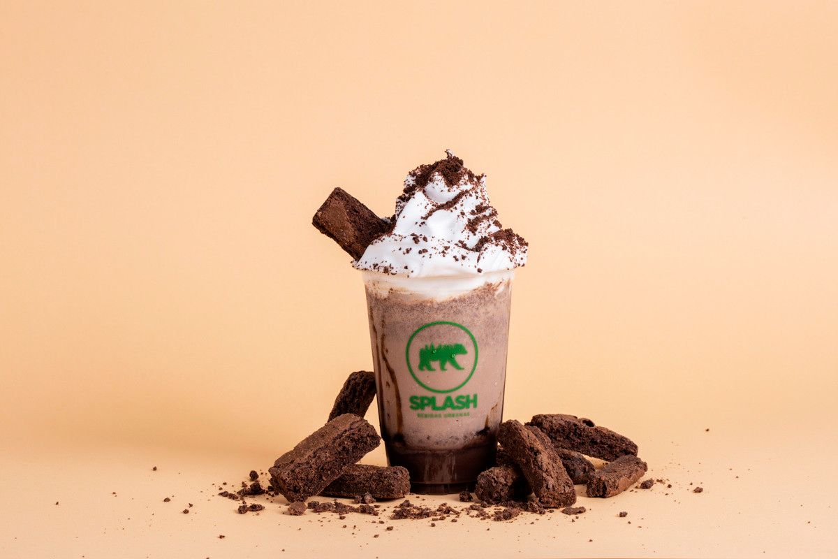 Milkshake coberto com chantilly e biscoitos de chocolate sobre um fundo bege.
