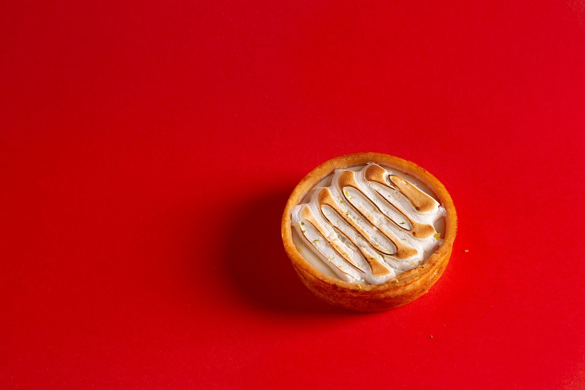 Pequeno biscoito ou doce redondo sobre um fundo vermelho vivo