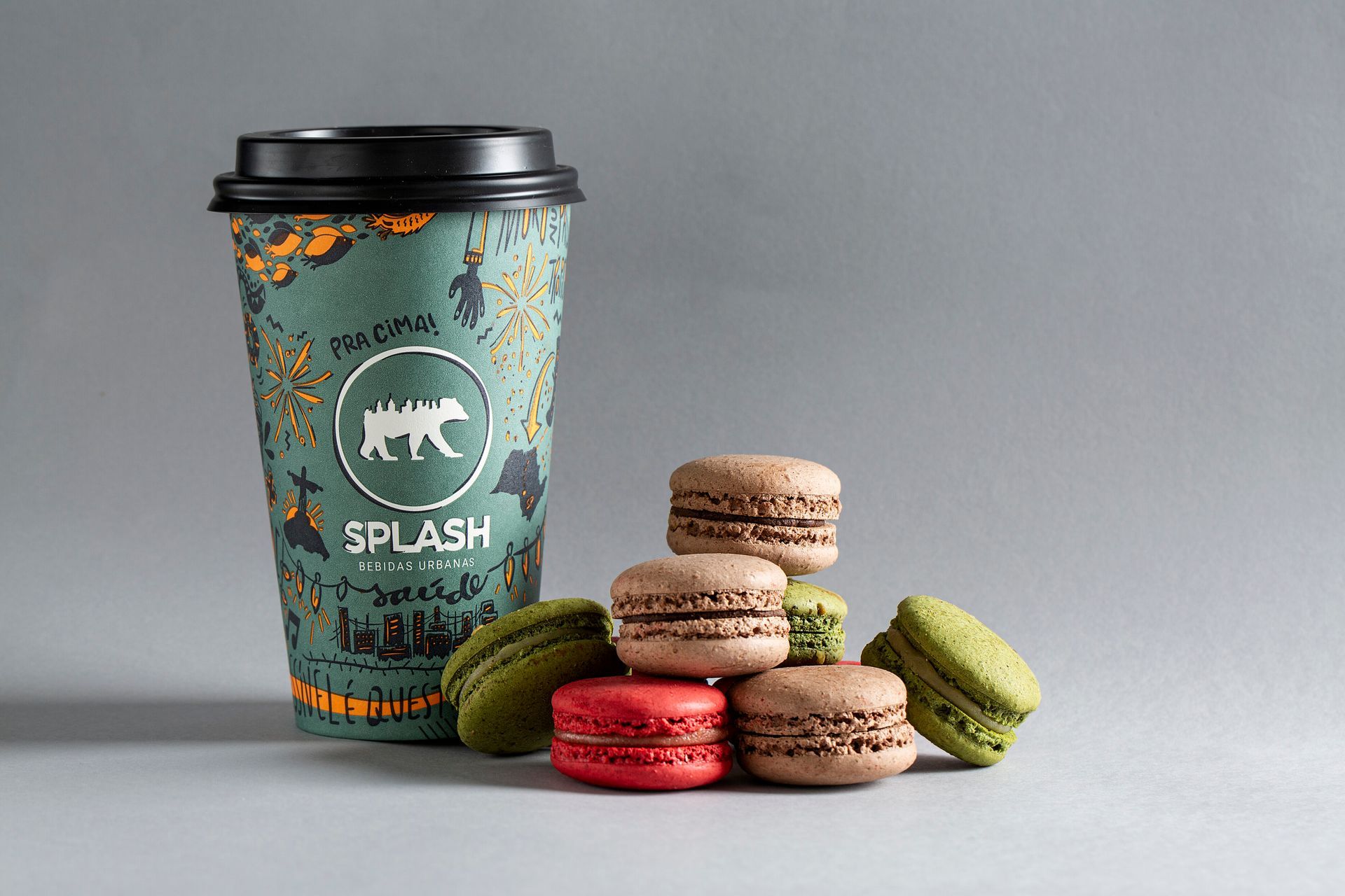 Xícara de café com macarons coloridos sobre um fundo cinza.