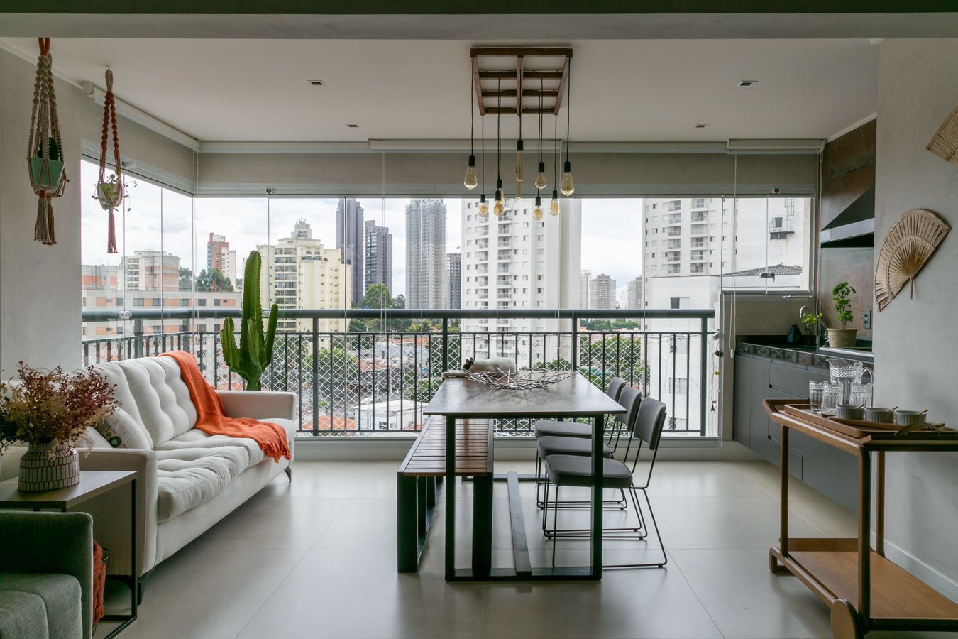 Sala de estar moderna com sofá, mesa de jantar, varanda com vista para a cidade e para o horizonte além das grandes janelas.