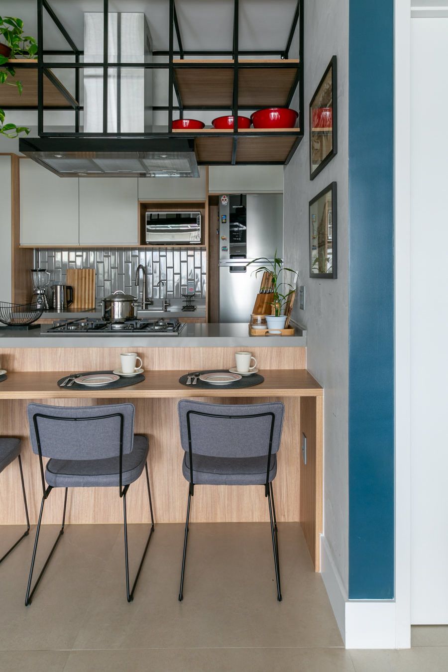 Cozinha moderna com prateleiras abertas, ilha de madeira e dois bancos pretos junto ao balcão de refeições rápidas.