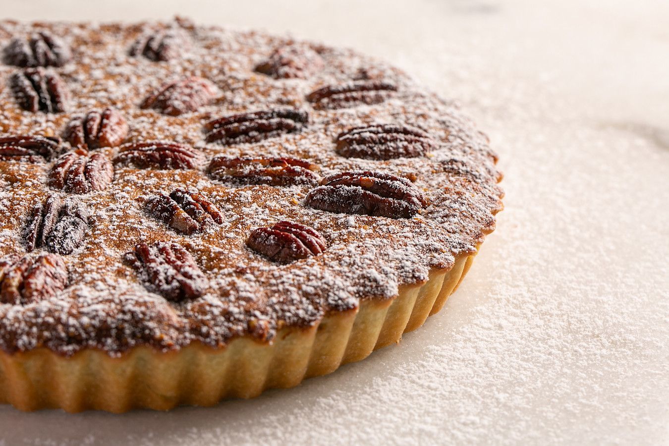 Tarte com passas e polvilhada com açúcar de confeiteiro sobre uma superfície leve.