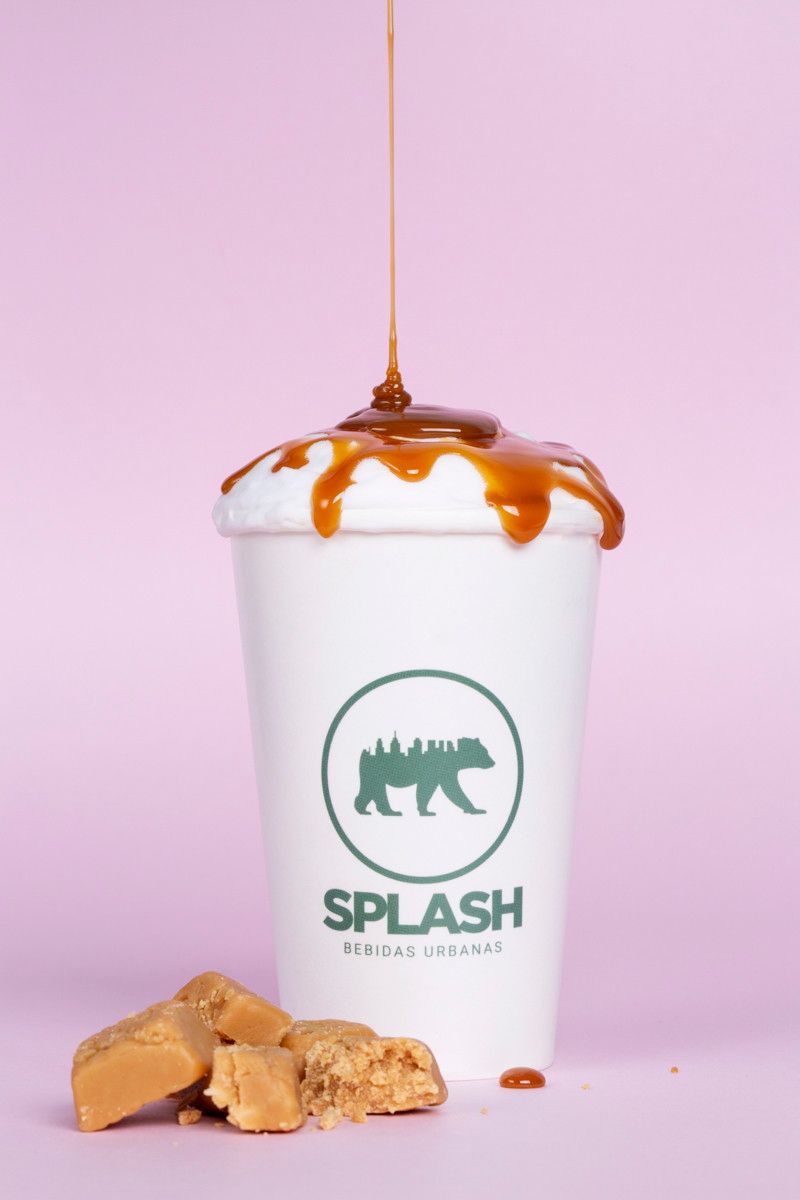 Taça White Splash com calda de caramelo e pedaços de doce sobre fundo rosa.