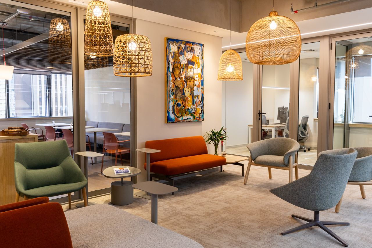 Sala de estar moderna com cadeiras coloridas, luminárias pendentes de vime, um sofá e um tapete estampado.