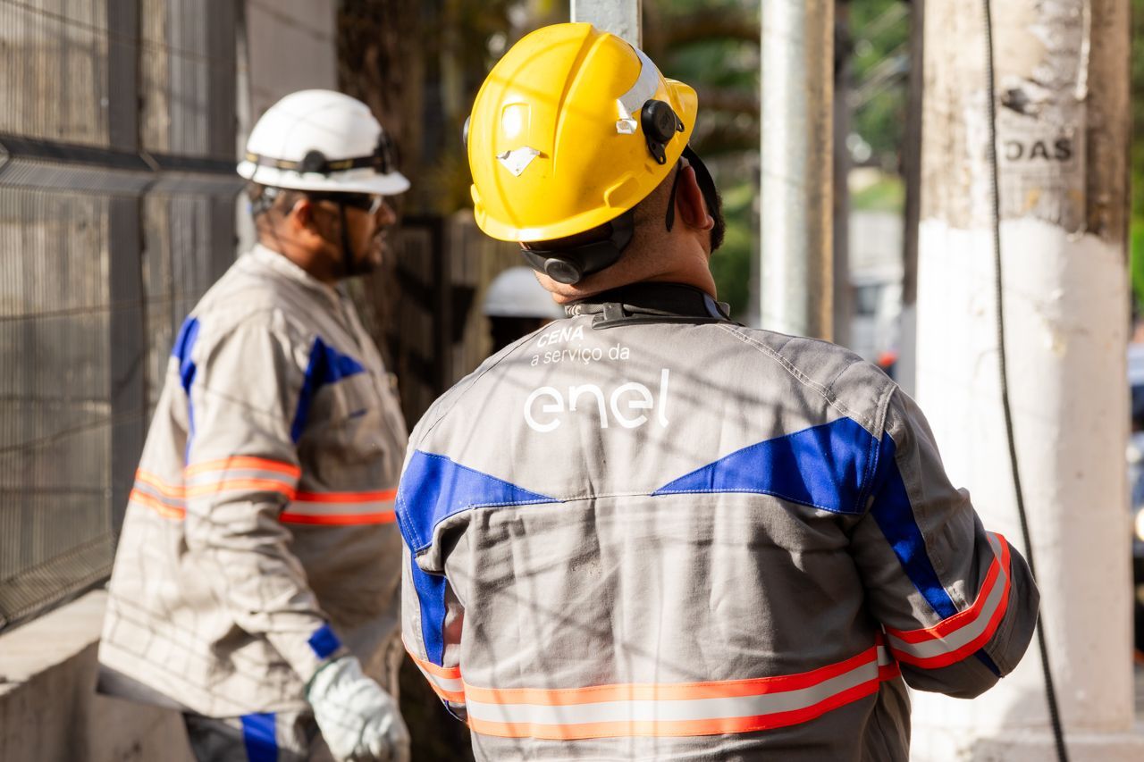Dois operários da construção civil com capacetes e coletes refletivos em um canteiro de obras ativo.