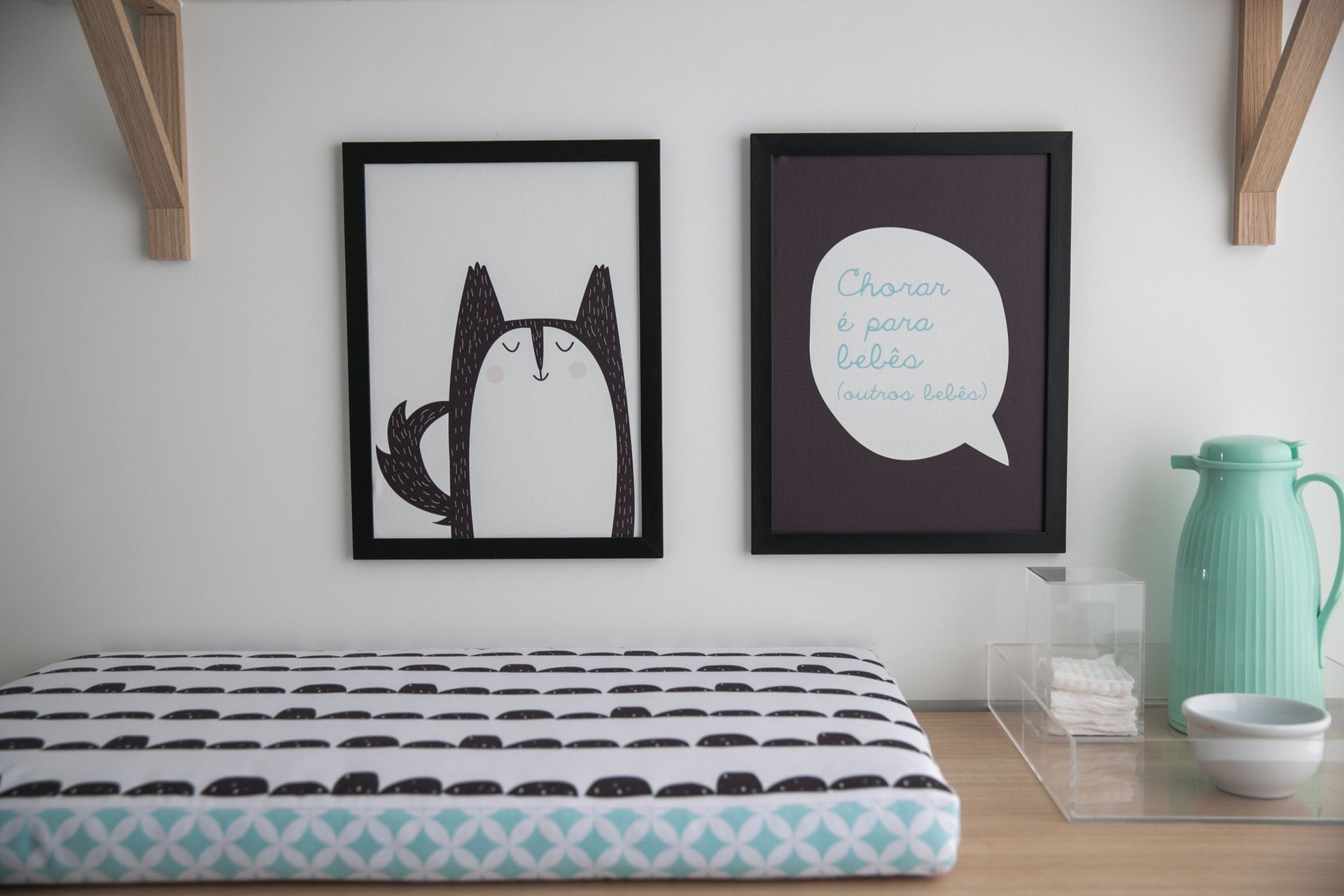 Prateleira de mesa com quadro de arte de gato e uma impressão de balão de fala acima de almofadas estampadas, uma jarra e uma tigela verde-menta.