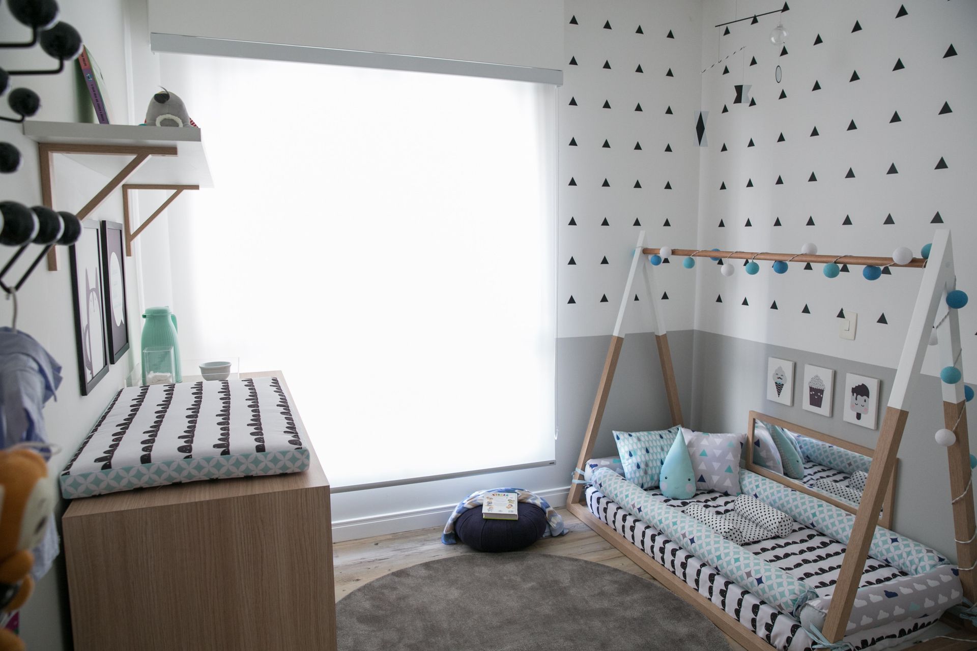 Quarto de bebê aconchegante com berço, trocador e janela iluminada em um ambiente branco.