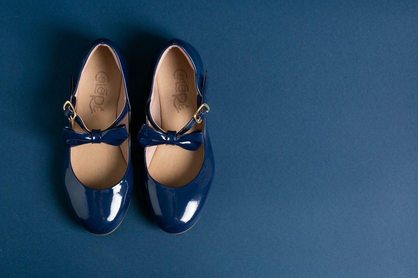 Par de sapatos Mary Jane de verniz azul sobre um fundo azul.