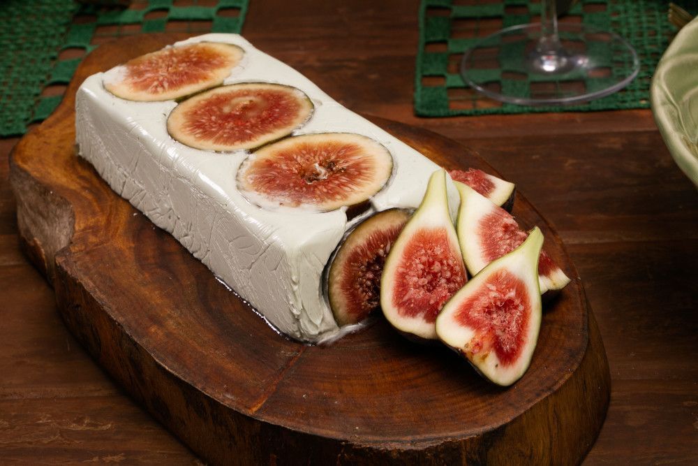 Bolo rocambole de figo coberto com fatias de figo, servido em uma tábua de madeira.