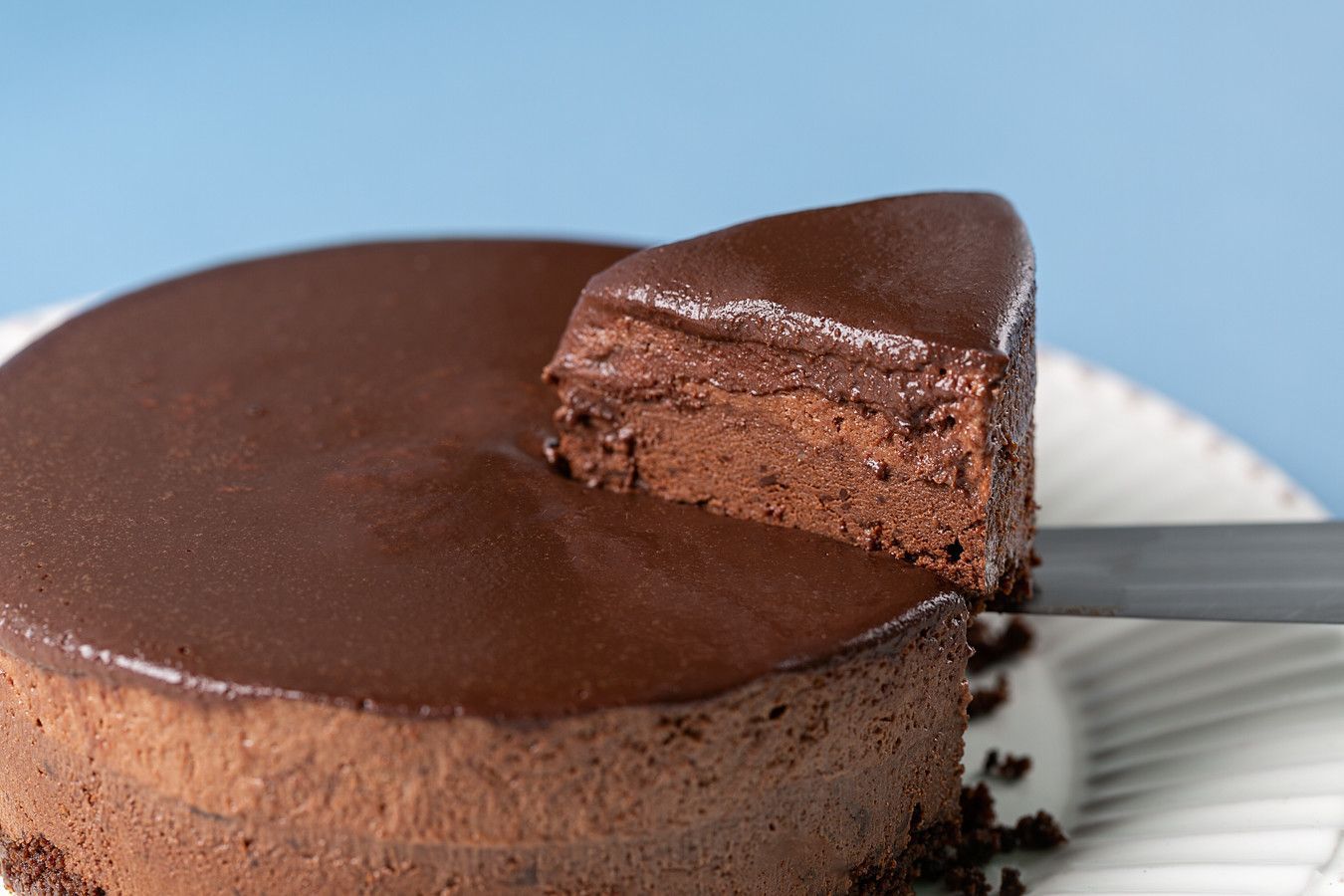 Bolo de chocolate com uma fatia retirada, mostrando o interior úmido, sobre um prato branco.