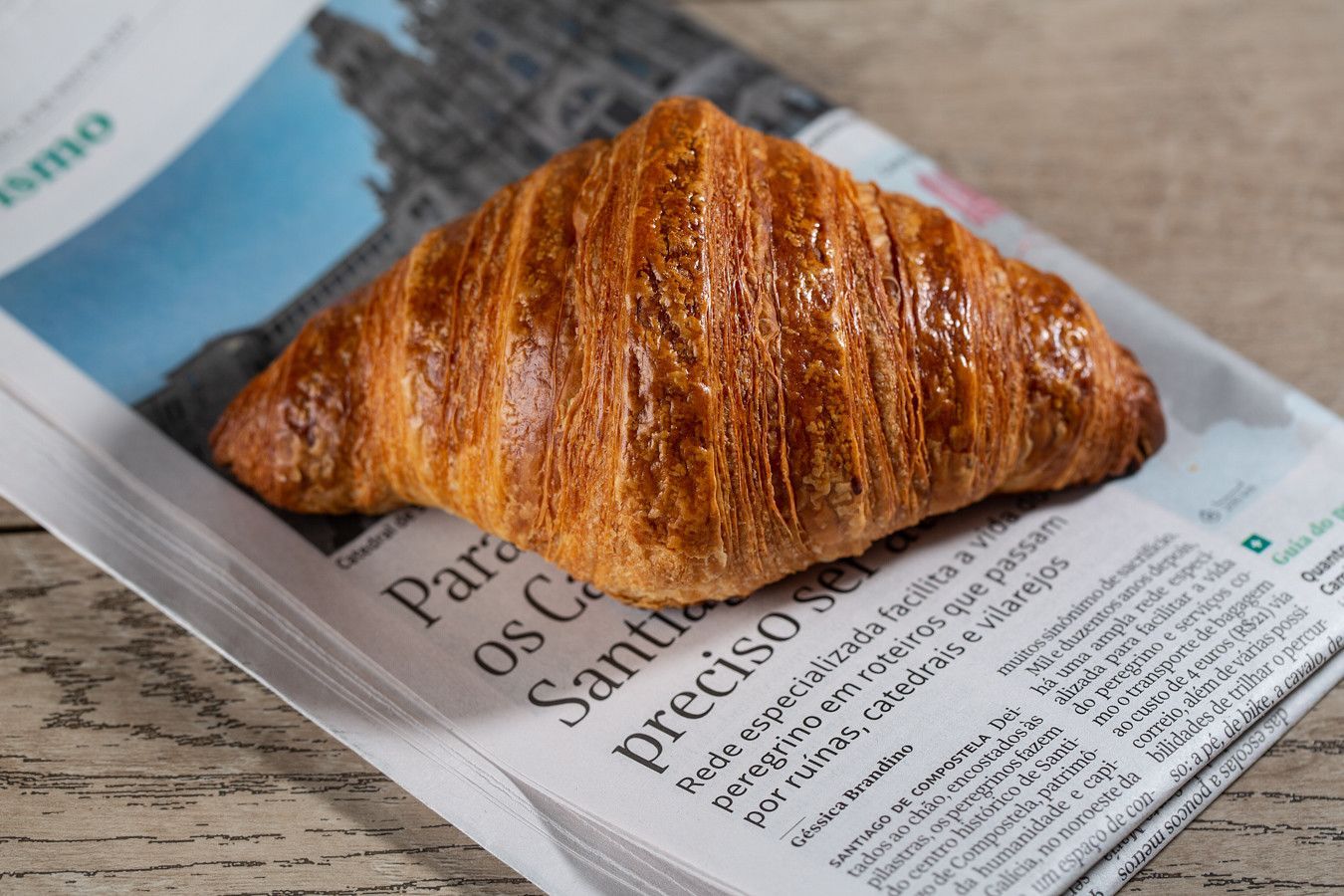 Croissant dourado sobre um jornal em cima de uma mesa