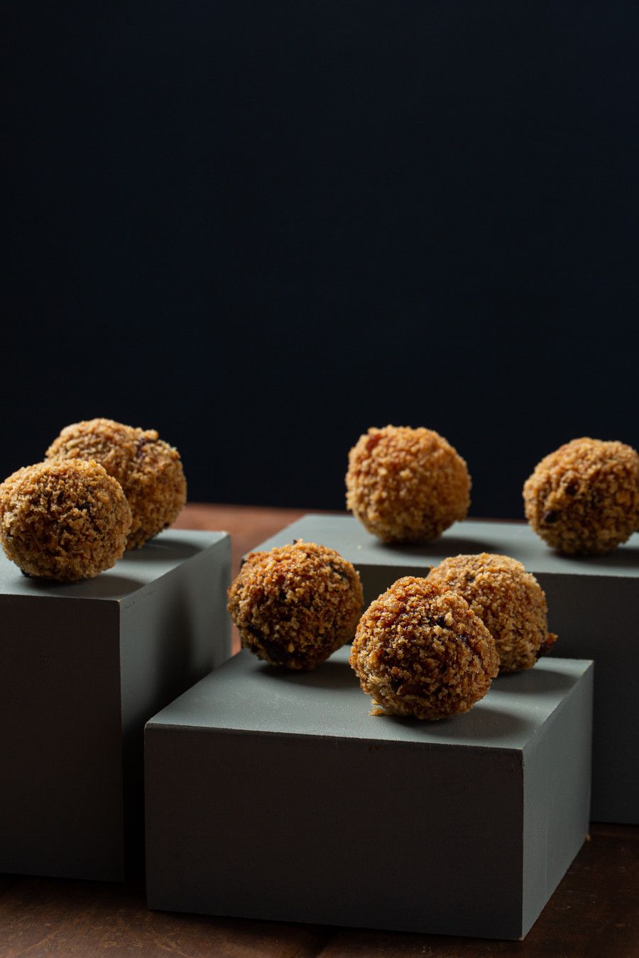 Trufas de sobremesa douradas em blocos cinzentos sobre um fundo escuro.