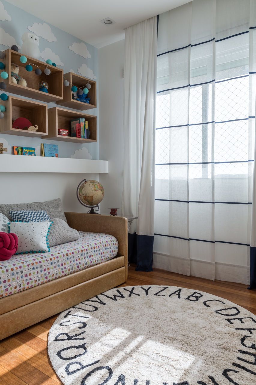 Quarto infantil aconchegante com cama, prateleiras de brinquedos e uma grande janela com cortinas translúcidas.