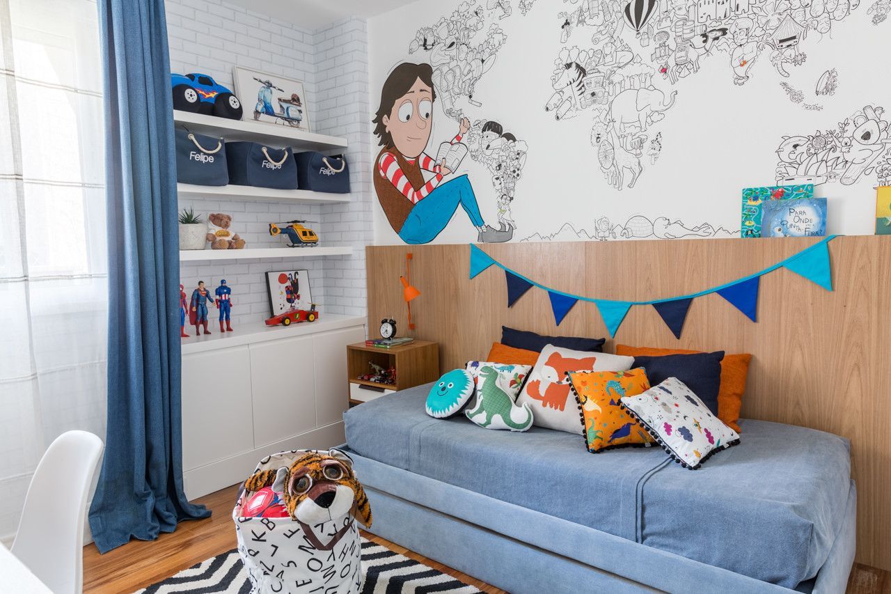 Quarto infantil iluminado com beliche, cortinas azuis, parede com mural e almofadas coloridas.